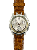 A Swatch wristwatch featuring a brown textured alligator leather strap and a silver-toned stainless steel case with a white dial.