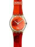 A wristwatch with a bright orange-red silicone strap and matching dial, featuring a silver-tone round case and Swatch branding on the dial and Zerkon on the buckle.