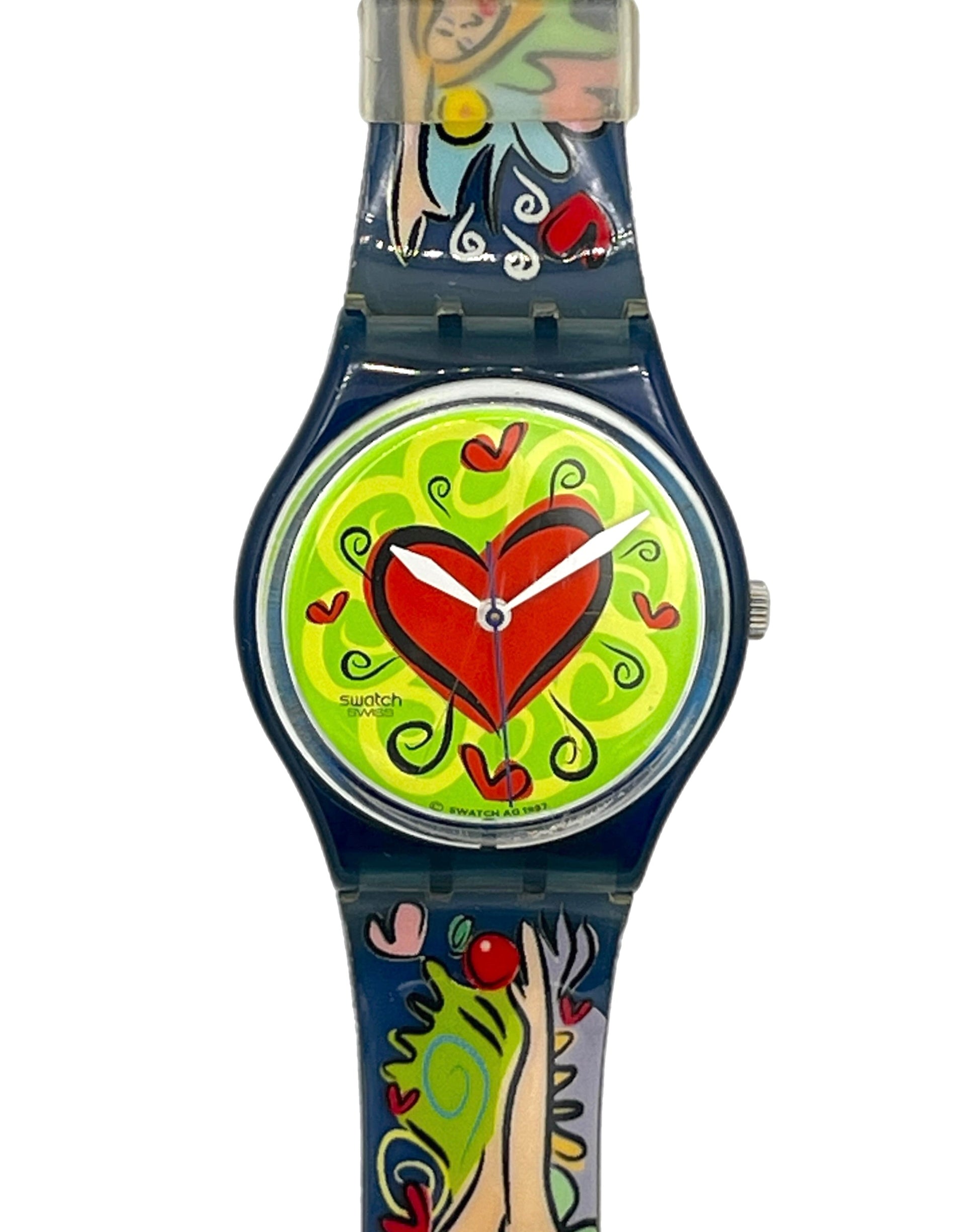 A Swatch wristwatch with a dark blue case and a colorful, whimsical strap and dial design featuring a large red heart on a lime green background.
