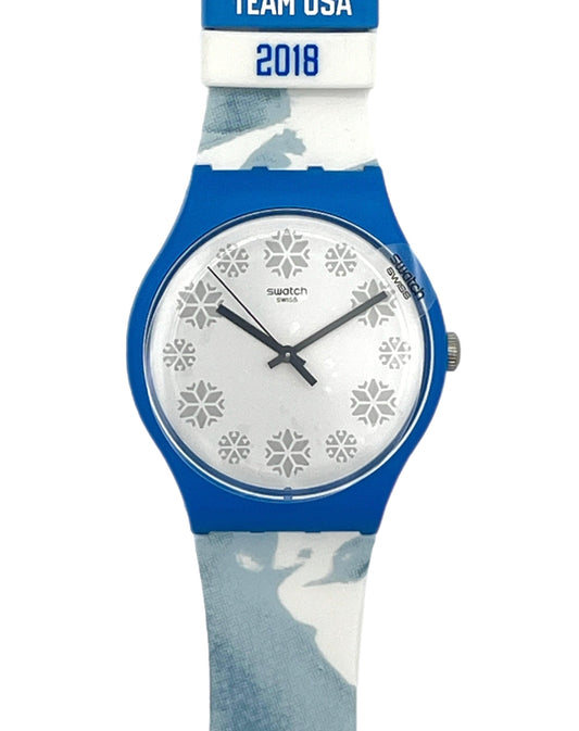 Swatch Swatch Team USA 2018 wristwatch with a blue case, white dial with snowflake patterns, and a blue and white camouflage strap.