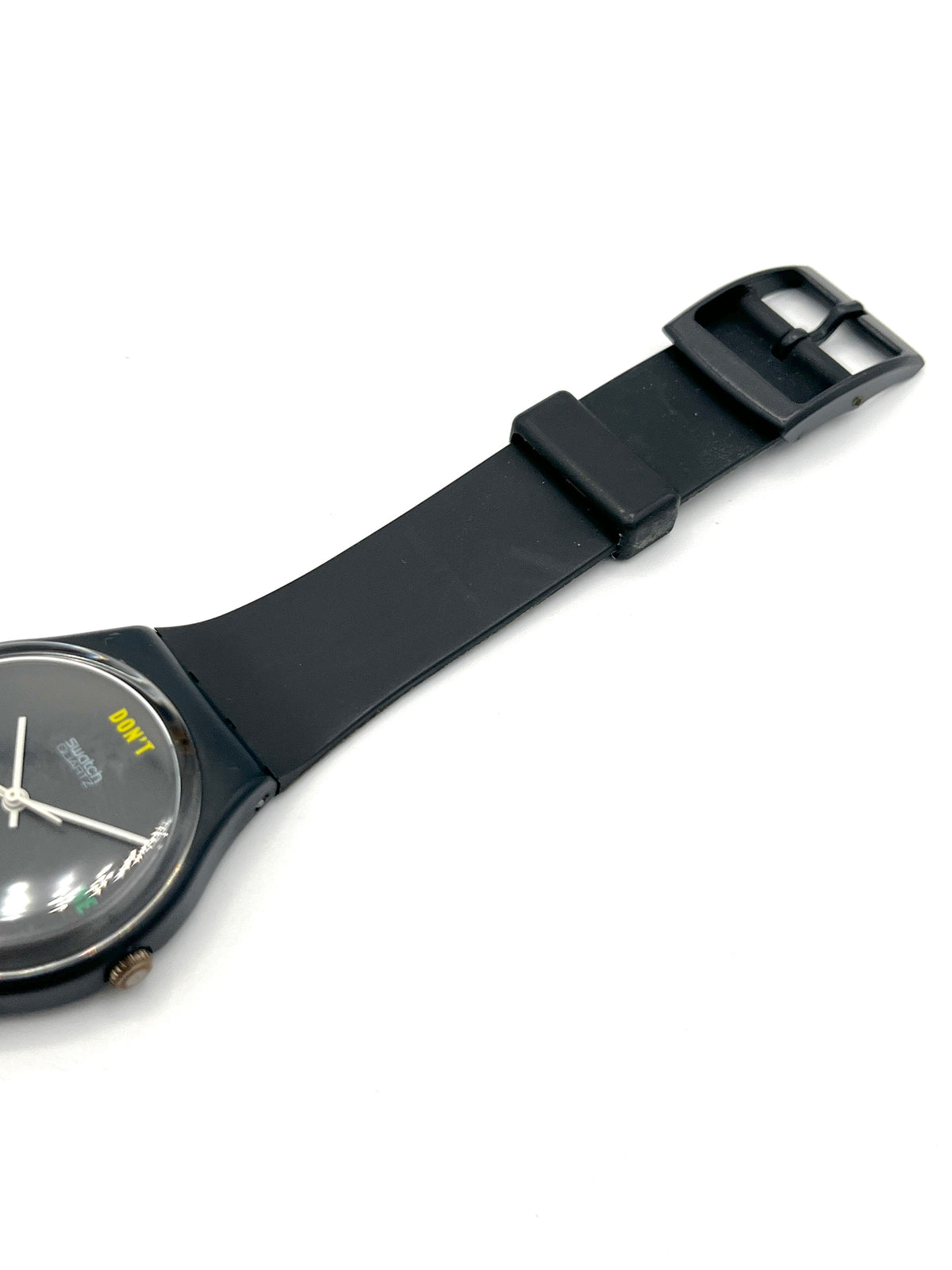 A black analog watch with a matte black strap and a dark dial, photographed diagonally on a clean white background.
