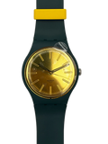 A Swatch wristwatch featuring a dark teal-green silicone strap, a gold-tone dial, and a bright yellow accent on the strap near the case, shown against a plain white background.
