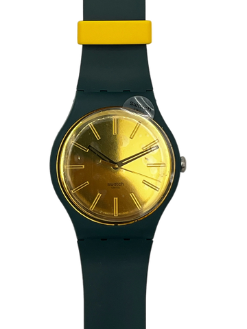 A Swatch wristwatch featuring a dark teal-green silicone strap, a gold-tone dial, and a bright yellow accent on the strap near the case, shown against a plain white background.