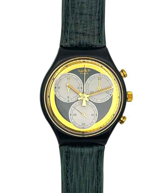 Swatch wristwatch with a black case, textured dark green strap, and a gold-tone dial featuring three silver subdials.