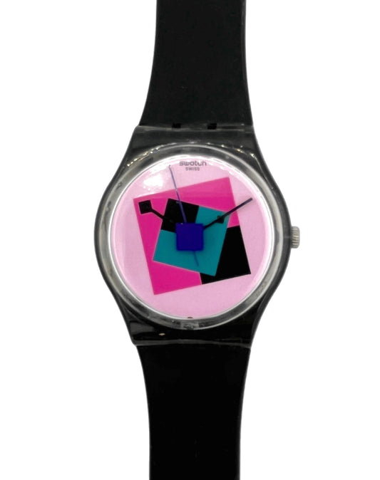 A wrist watch with a black strap and a round silver-tone case, featuring a colorful geometric dial with pink, blue, and black shapes on a light background.