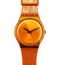 A Swatch wristwatch featuring a vibrant orange glitter strap and a matching orange dial with black hands, shown against a plain white background.