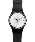 A Swatch wristwatch with a black round case, black strap, and a white dial featuring black Arabic numerals and gold-tone hands.