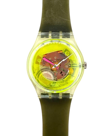 A Swatch wristwatch with a translucent olive green silicone strap and a bright yellow-green dial showing the inner mechanical movement.