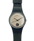 A Swatch watch with a black strap and case, featuring a textured beige dial with black hands and a black logo at the bottom.