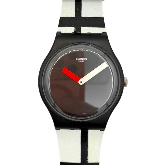 Swatch Centre Pompidou wristwatch with a black round case, a dark brown dial with white and red hands, and a white strap featuring black and red geometric stripes.