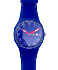A Swatch wristwatch with a vibrant blue silicone strap and matching blue dial, featuring white Arabic numerals and contrasting red hands.