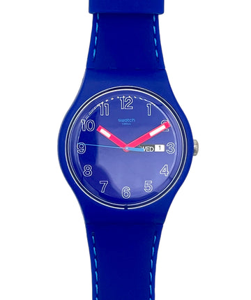 A Swatch wristwatch with a vibrant blue silicone strap and matching blue dial, featuring white Arabic numerals and contrasting red hands.