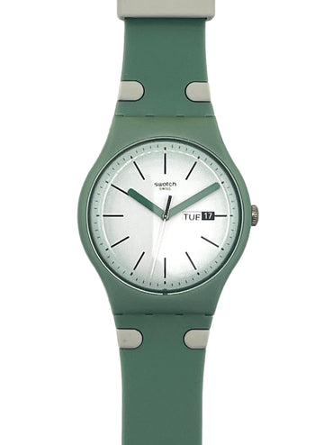 A Swatch wristwatch featuring a sage green silicone strap and matching green case with a white dial, shown against a plain white background.