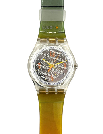 A Swatch wristwatch with a translucent olive green and yellow-green strap, a clear case, and a detailed multicolor sun face dial.