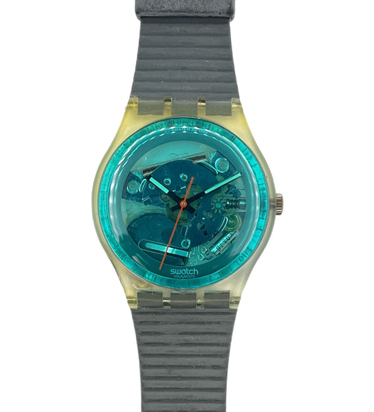 Swatch watch with a transparent teal face and gray strap on a white background