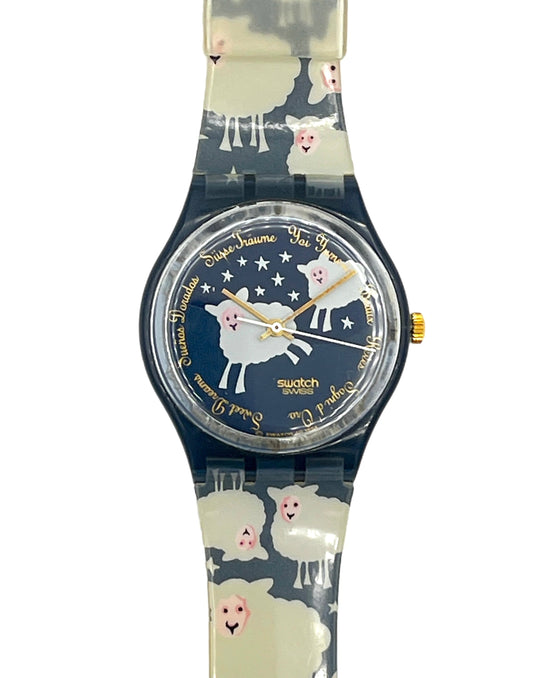 Swatch watch featuring a sheep and stars pattern on a navy blue dial with gold accents, set against a plain white background.