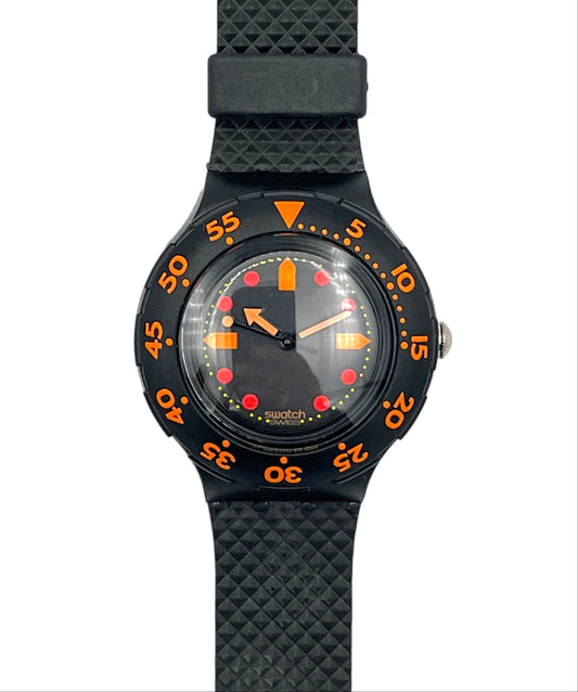 A Swatch wristwatch with a black textured strap, black bezel, and a black dial featuring bright orange and red accents.